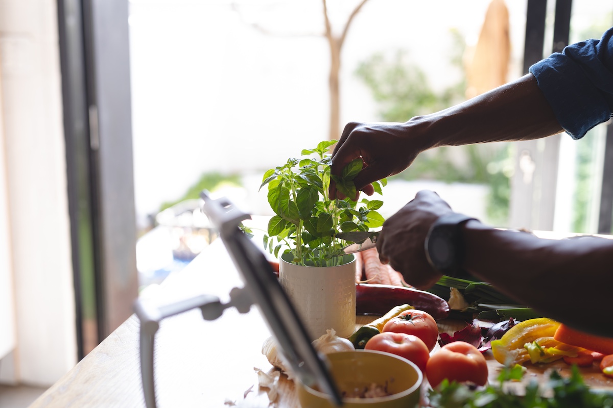 Happy african american man standing in kitchen and cooking dinner. Spending quality time at home alone.