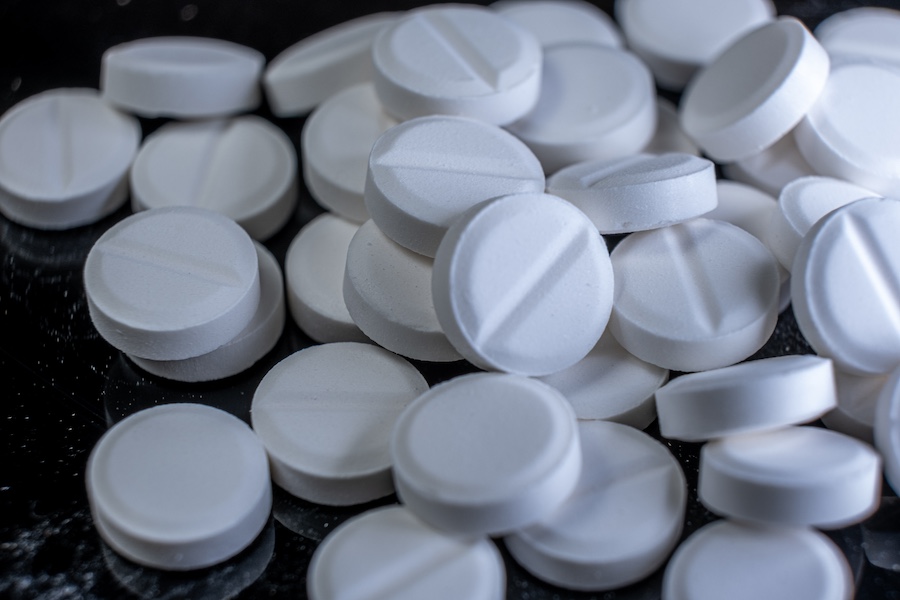 some white pills on a black background. aspirin more thana pain killer